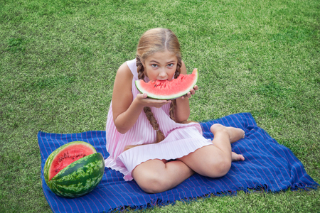 portrait of beautiful girl holding and eating watermelon in the park.の写真素材