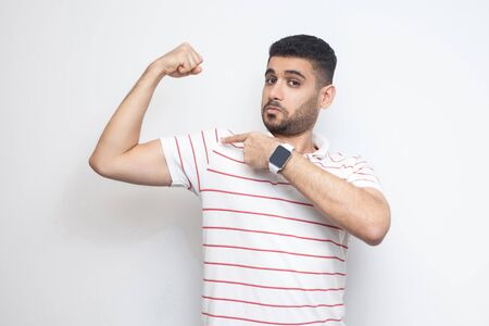 I am strong. Portrait of proud handsome bearded young man in striped t-shirt standing, pointing at...