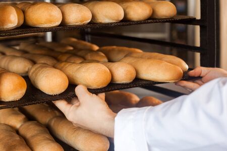 Closeup of hands of professional chef man in white uniform standing near shelves full with fresh...