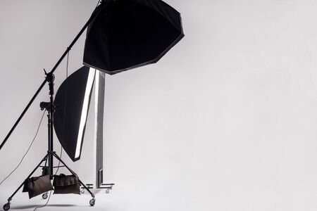 Professional photo studio with light setup included octagon softbox on boom, strip soft box and reflector on light gray background. indoor studio shot with copy space.の写真素材
