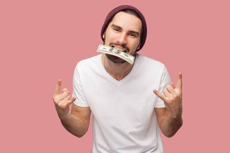 Crazy confident handsome bearded young hipster man in white shirt and casual hat standing, holding...