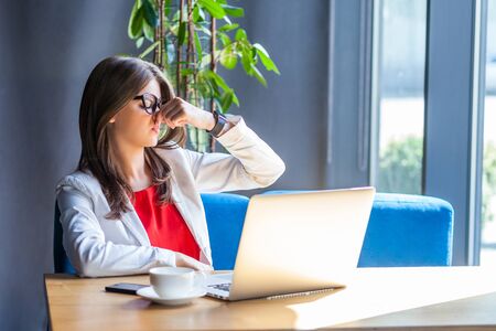 Bad smell. Portrait of dissatisfied beautiful stylish brunette young woman  in glasses sitting pinching her nose and don't want to smelling. indoor  studio shot, cafe, office background.: Royalty-free images, photos and  pictures