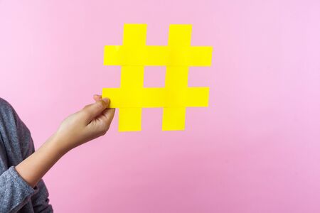 Closeup of tiny female hand holding big large hashtag sign, hash symbol of promotion and popularity...