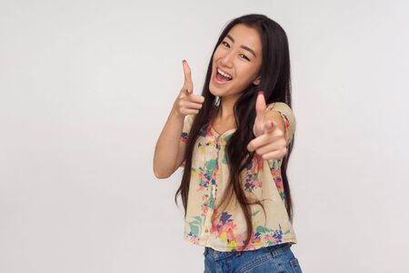 Delighted enthusiastic asian girl in summer blouse pointing at camera with finger guns, choosing...