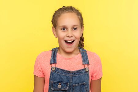 Wow, unbelievable! Portrait of surprised child in denim overalls standing with mouth open in...