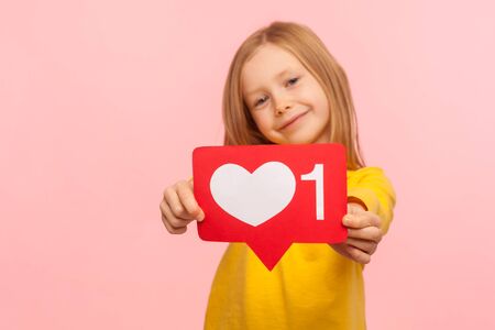 Child blog, trendy content. Portrait of adorable cheerful little girl showing heart like icon of...