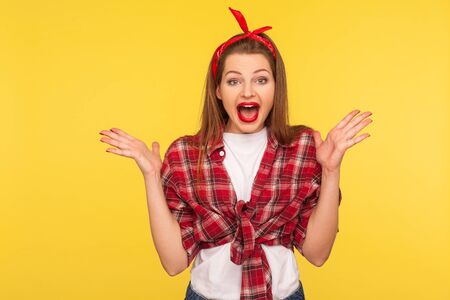 Oh my god, wow! Portrait of surprised pinup girl in checkered shirt and headband screaming in surprise, shocked by crazy news. retro vintage 50's style, studio shot isolated on yellow backgroundの写真素材