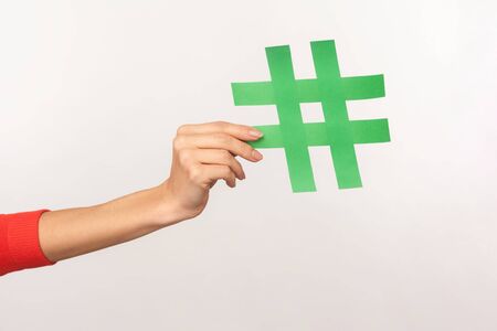 Follow trend, join popular blog! Closeup of female hand holding green hashtag sign, sharing tagged...
