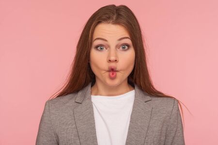 Closeup portrait of funny pretty young woman in business suit making fish face with pout lips,...