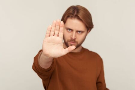 I refuse! Portrait of man with beard in sweatshirt showing definitive no, confident stop gesture and looking with negative expression, warning and declining conflict. indoor studio shot isolatedの写真素材