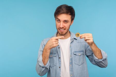 Attention at cryptocurrency. Cheerful businessman in denim shirt pointing at bitcoin, smiling...
