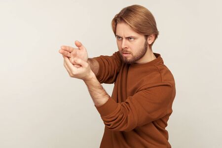 Aimed shot. Portrait of concentrated focused bearded man pointing finger gun gesture to target, threatening to kill, shooting with hand pistol and looking menace. indoor, isolated on gray backgroundの写真素材