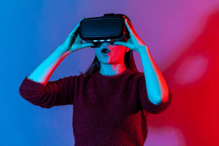 Girl wearing virtual reality glasses on head playing fighting game, holding clenched fists up ready...