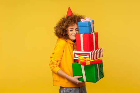 Happy emotions from big mountain of gifts. Portrait of pleased happy curly-haired woman with party...