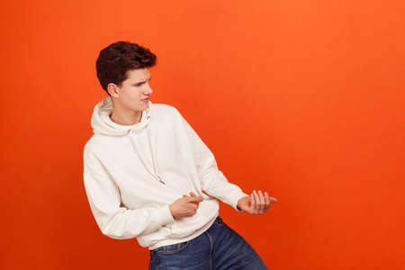 Strong persistent young man in casual style sweatshirt with hood pulling something, purposeful...