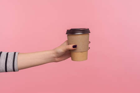 Closeup hand giving coffee in disposable cup, hot drink with caffeine to boost energy in morning,...
