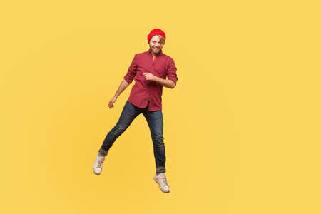 Portrait happy joyful hipster trendy guy levitating, looking at camera with toothy smile, hovering...