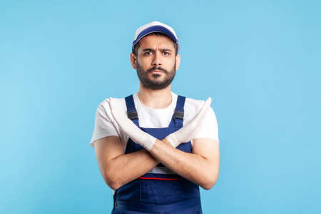 No way, prohibited! Handyman in overalls and gloves gesturing stop with crossed hands. Profession of service industry, courier delivery, housekeeping maintenance. Worker in uniform warning of banの写真素材