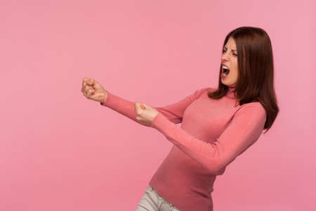 Strong purposeful woman with brown hair in pink sweater making great efforts to achieve success,...