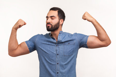 Strong and independent self confident man with beard showing biceps raising strong arms, proud of...