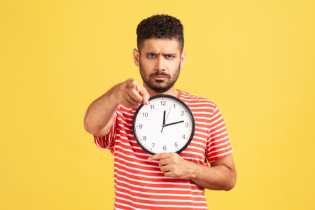 Hey you, time to work! Angry annoyed man with beard in striped t-shirt pointing finger at you...