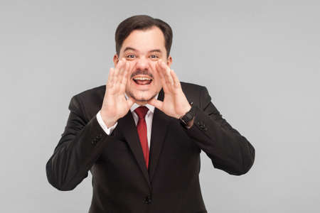 Hey you! Worry businessman shout at camera. Indoor, studio shot, isolated on gray background. handsome businessman with black suit, red tie and mustache looking at camera.の写真素材
