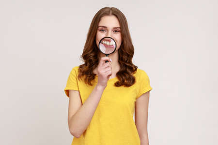 Smile, zoom, tooth care. Portrait of young aged woman in casual yellow T-shirt standing and holding...
