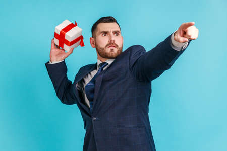 Catch your gift! Young serious businessman wearing dark official style suit, swung and wants to...