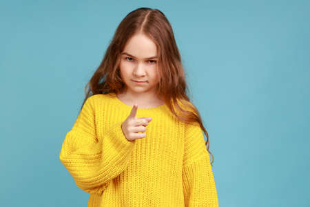 Portrait of little girl standing with admonishing gesture, warning, looking with strict expression,...