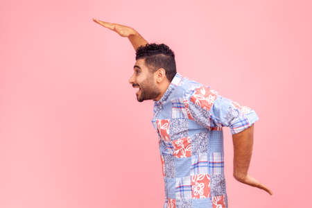 Side view of cheerful bearded man in blue casual shirt dancing, having fun and doing funny egyptian...