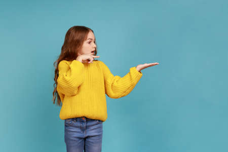 Portrait of little girl presenting free space, points aside, copy space for advertisement,...