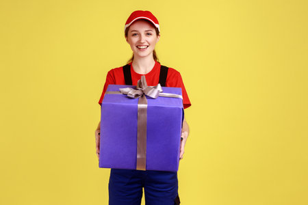 Satisfied optimistic courier woman bringing parcel door-to-door, giving big present box, delivering...
