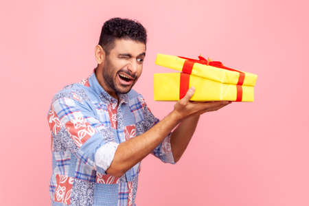 Portrait of curious happy man opening gift, peeking inside box with nosy look, unpacking present, in...