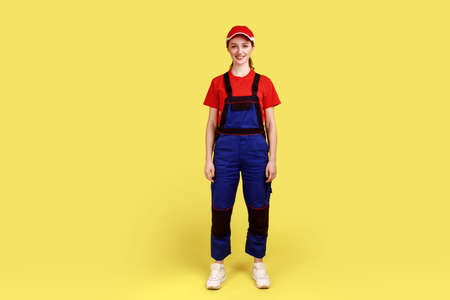 Full length portrait of worker woman standing and looking at camera with positive facial expression,...