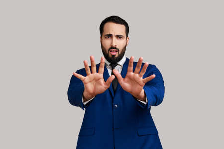 Portrait of bearded man raising hands from sudden fear, looking terrified, scared to death, horror...
