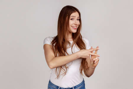 Portrait of charming happy woman crossing fingers to make hashtag sign and looking at camera with...