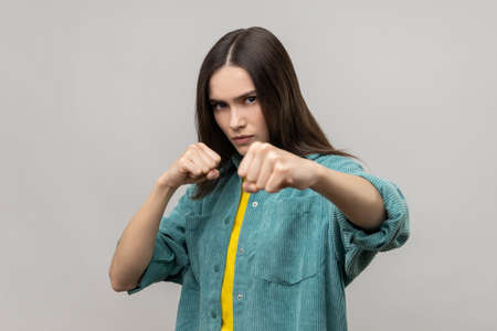 Portrait of angry woman standing with clenched fists and furious look, ready to punch, expressing...