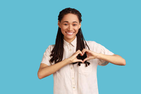 Beautiful woman with black dreadlocks gesture heart over chest, expresses love, says be my...