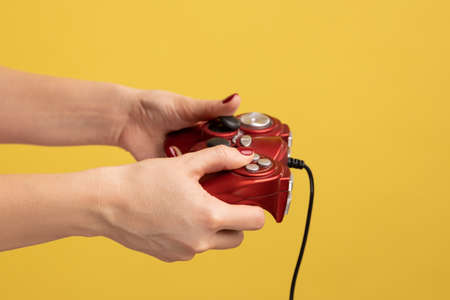 Profile side view closeup portrait of woman hand holding red gamepad joystick for playing video...