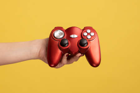 Profile side view closeup portrait of woman hand holding showing red gamepad joystick for playing...