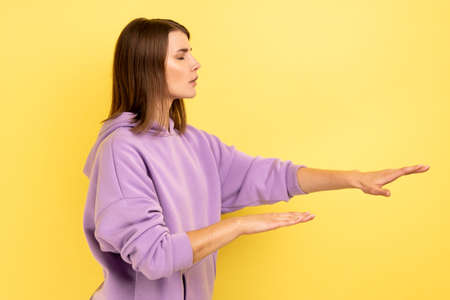 Side view of woman with eyesight problems trying to move with closed eyes touching space around with...