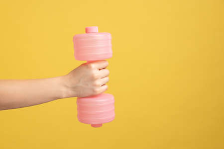 Closeup of woman hand holding pink dumbbell , equipment for home workout, fitness and activity,...