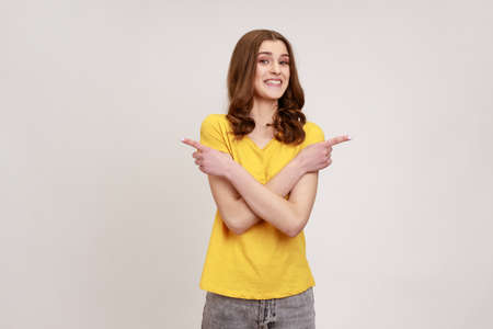 Portrait of positive extremely happy woman of young age in yellow T-shirt standing with crossed...