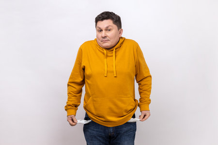 I have no money more. Portrait of sad bankrupt man standing and showing his empty pocket and looking...
