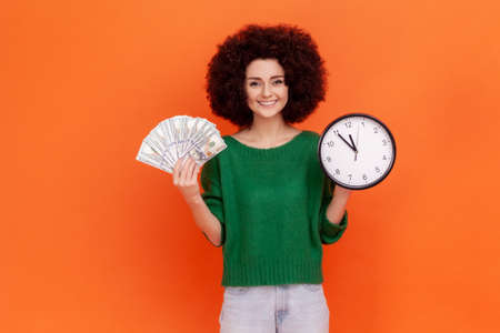 Smiling positive young adult woman with Afro hairstyle wearing green casual style sweater holding...