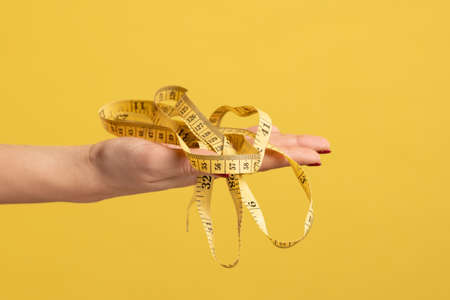 Closeup profile side view portrait of woman hand holding measure tape, fitness or tailor equipment....