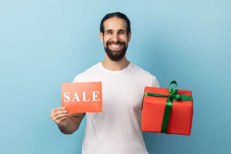 Bonuses on Black Friday shopping. Portrait of man wearing white T-shirt showing Sale inscription and...