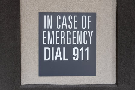 Gray sign on the wall depicting the emergency number, sign with inscription: in case of emergency dial 911の写真素材