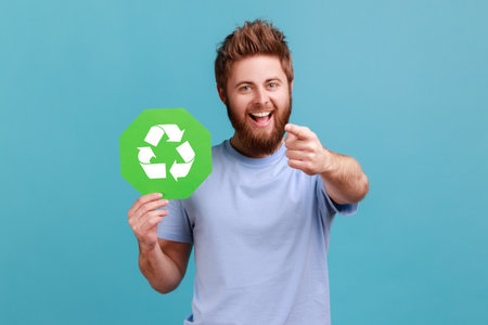 Portrait of extremely happy excited bearded man holding green recycling sign, saving environment,...