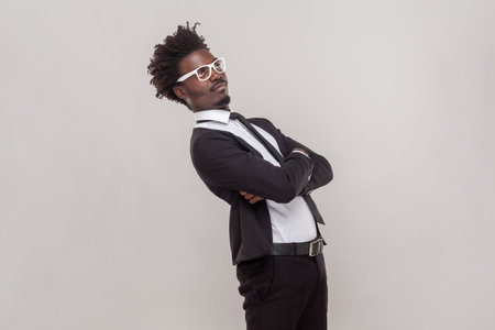 Side view portrait of funny man in glasses standing with crossed arms, looking away with confused...